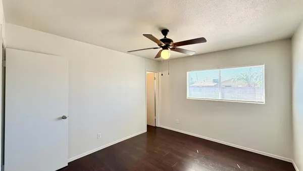 an empty room with wooden floor and a ceiling fan