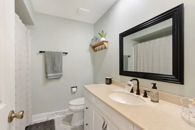 a bathroom with a granite countertop toilet sink and mirror