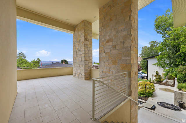 1389 Millbrook Way Bountiful, UT 84010 - Photo 12 of 74 Expansive outdoor patio featuring light-toned large format tile flooring, stone-clad architectural columns, a beige painted railing, and an elevated position