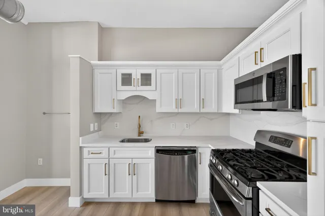 a kitchen with white cabinets stainless steel appliances and a sink
