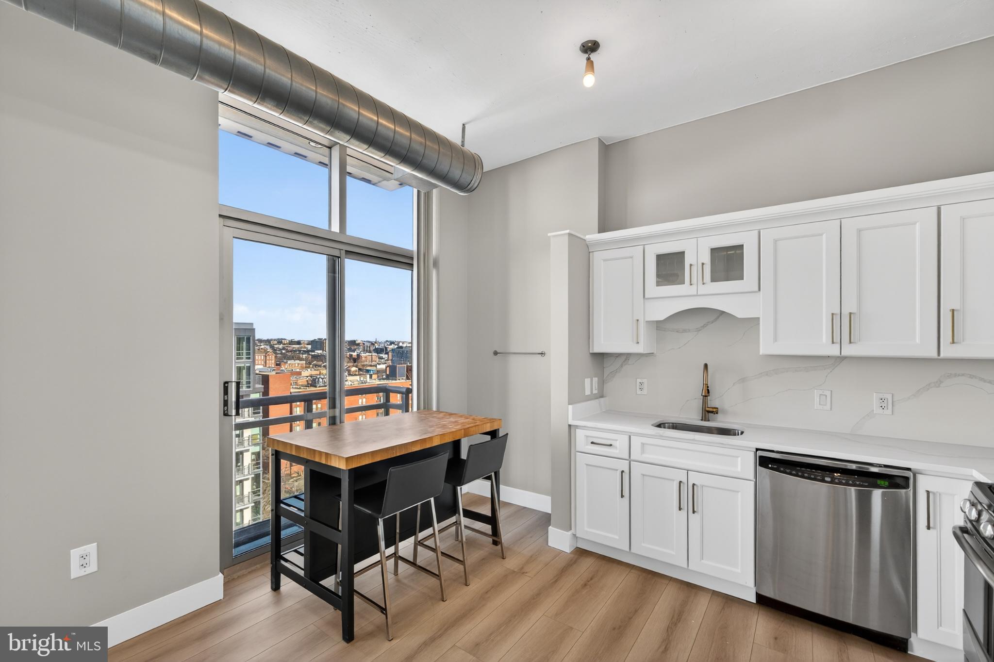 811 4th Street Northwest, Unit 1215 Washington, DC 20001 - Photo 17 of 32 a kitchen with a stove a sink and white cabinets with wooden floor next to windows