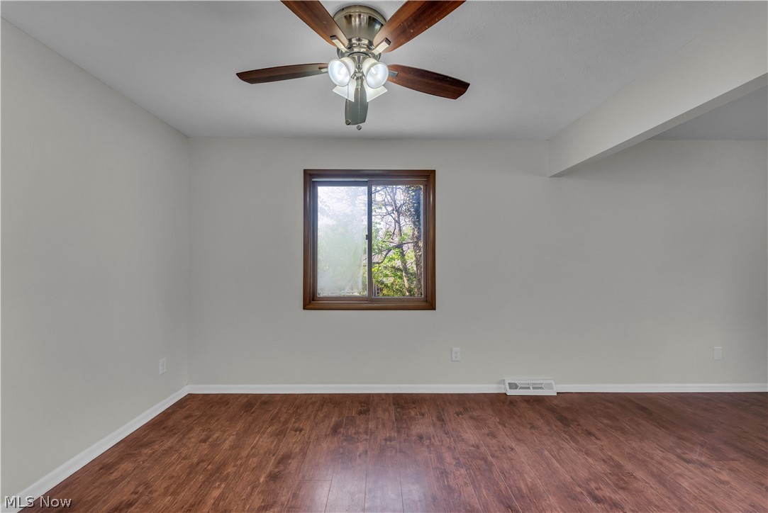 2540 Charney Road University Heights, OH 44118 - Photo 21 of 44 Interior room featuring wood-finish flooring, light-toned wall paint, white baseboards, a single window with wood trim, and a ceiling fan with integrated lighting