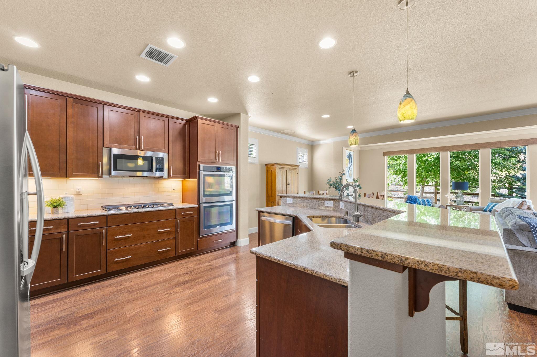 9207 Sassafras Trail Reno, NV 89523 - Photo 22 of 40 a kitchen with kitchen island granite countertop wooden cabinets a stove a sink and a refrigerator