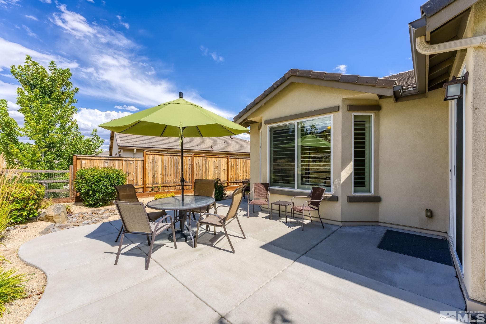 9207 Sassafras Trail Reno, NV 89523 - Photo 6 of 40 a view of a patio with a table and chairs under an umbrella with a small yard