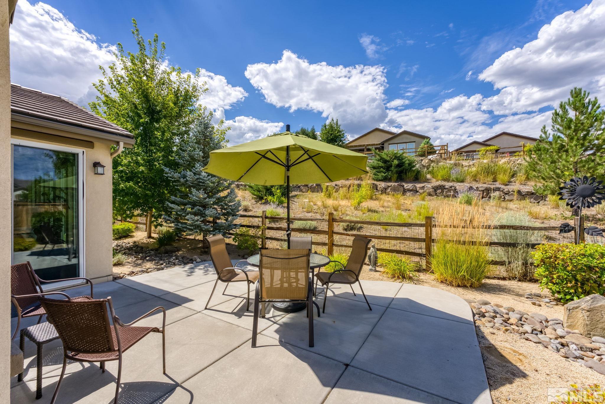 9207 Sassafras Trail Reno, NV 89523 - Photo 7 of 40 a view of a patio with a table and chairs under an umbrella with potted plants