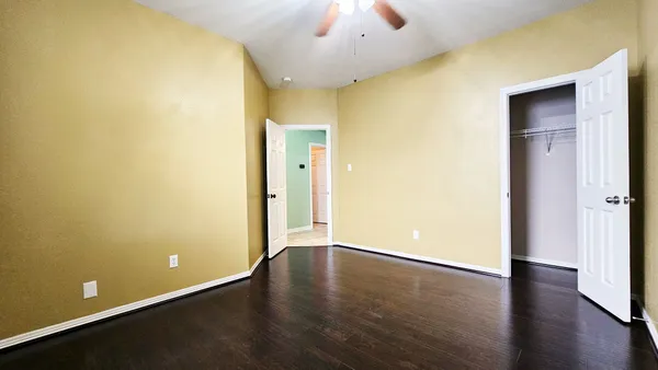 an empty room with wooden floor and a ceiling fan