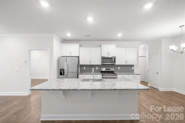 a large kitchen with granite countertop a large counter top stainless steel appliances and cabinets