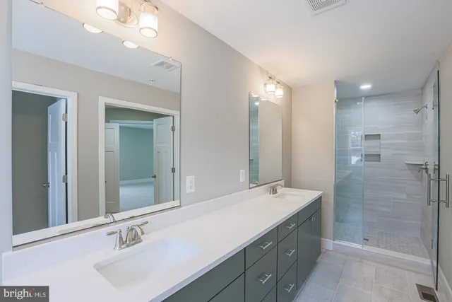 a bathroom with a double vanity sink mirror and shower