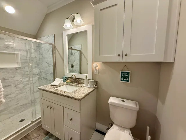 a bathroom with a granite countertop toilet sink and mirror