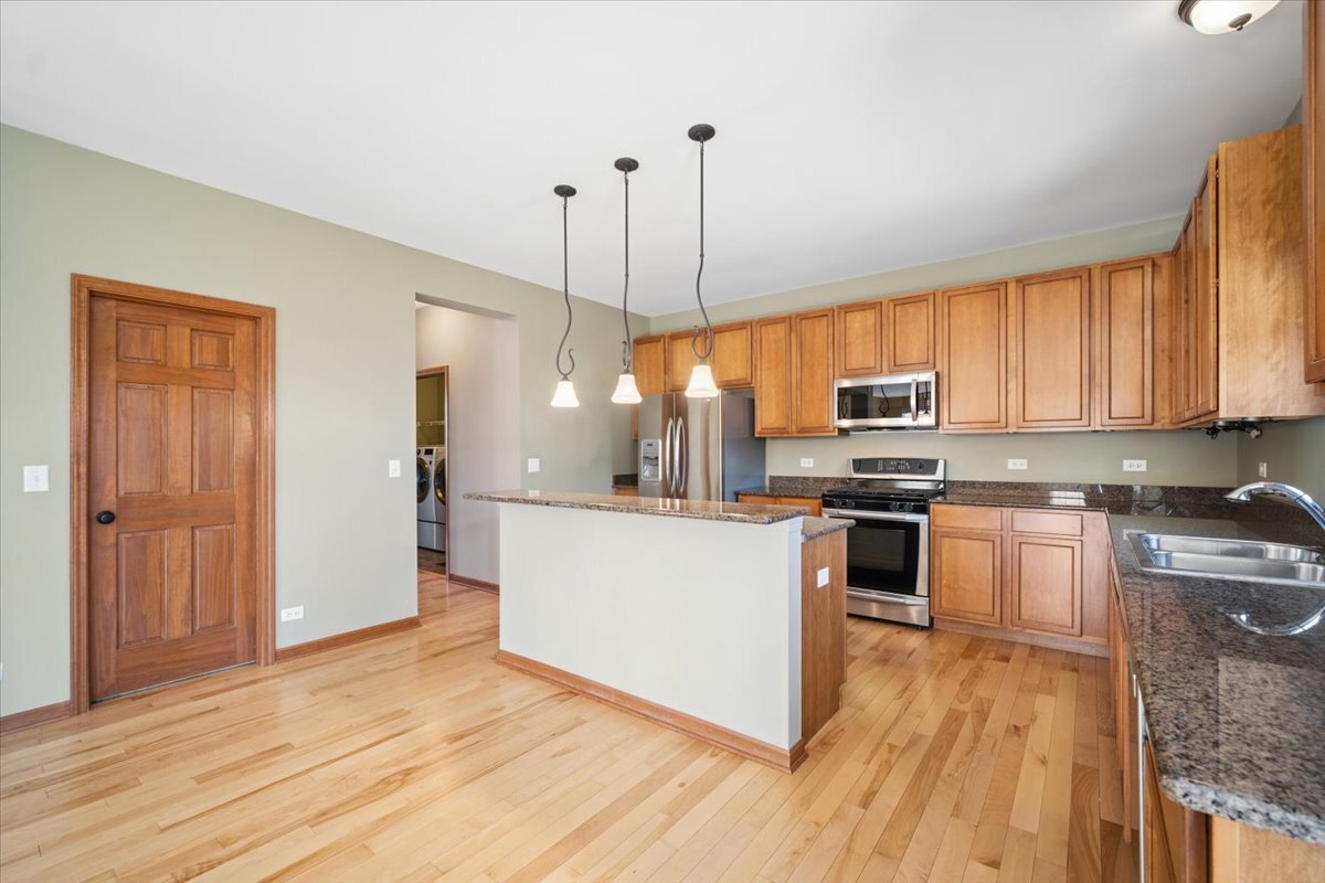3004 Crossfire Trail Elgin, IL 60124 - Photo 10 of 25 a kitchen with stainless steel appliances granite countertop a refrigerator a sink dishwasher a stove with wooden floor and cabinets next to a window