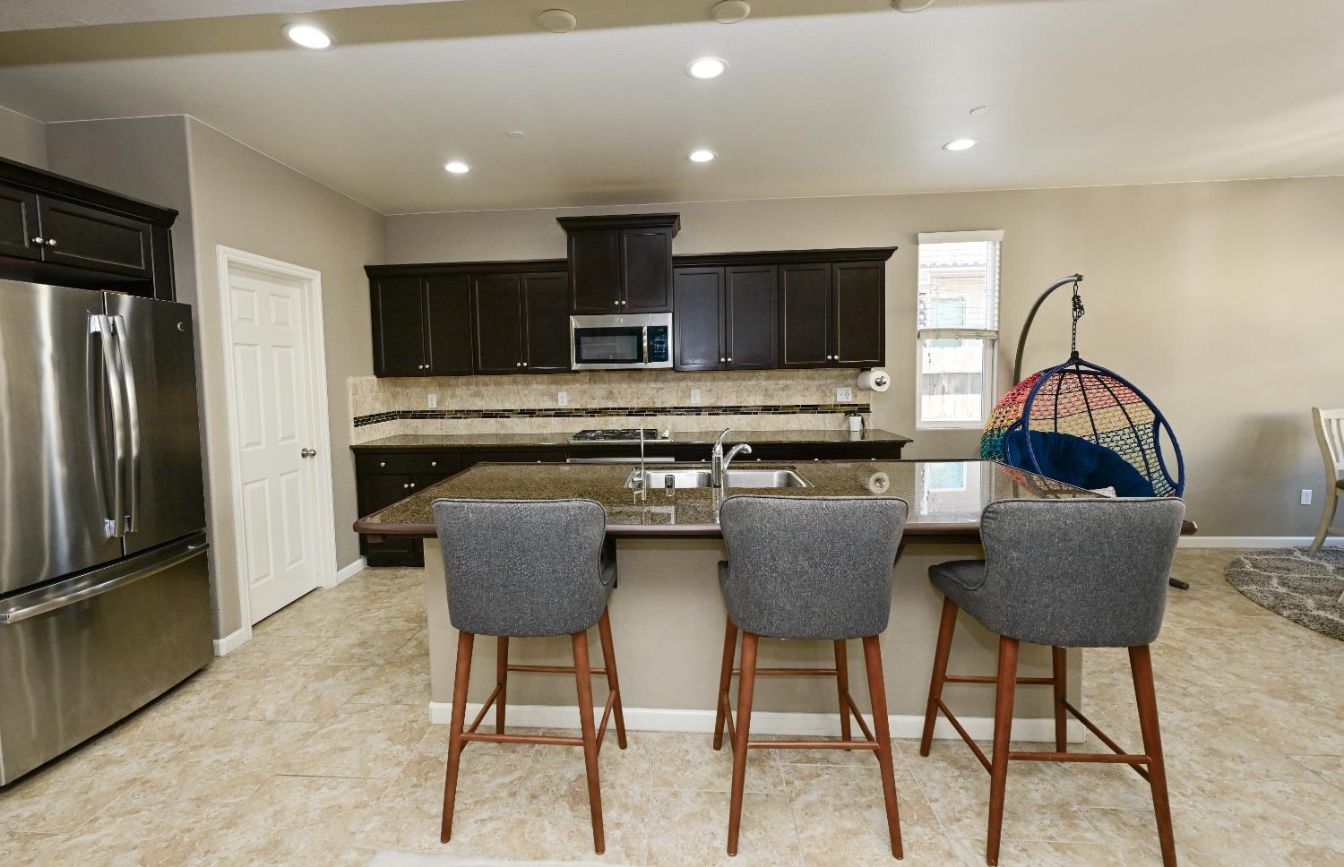 3569 Flint Avenue Clovis, CA 93619 - Photo 4 of 25 a kitchen with stainless steel appliances granite countertop a stove a refrigerator a microwave a dining table and chairs