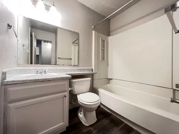 a bathroom with a granite countertop toilet a sink and a bathtub