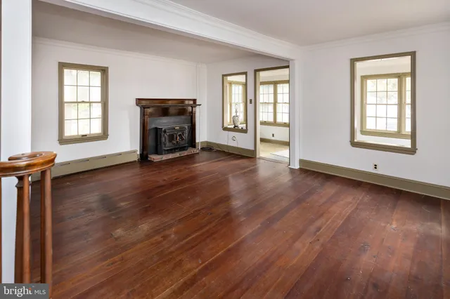 an empty room with windows a fireplace and wooden floor