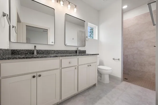 a bathroom with a granite countertop sink mirror and toilet