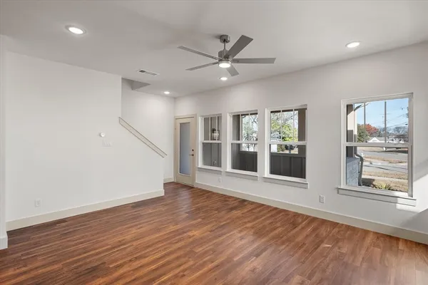 a view of an empty room with wooden floor and a window