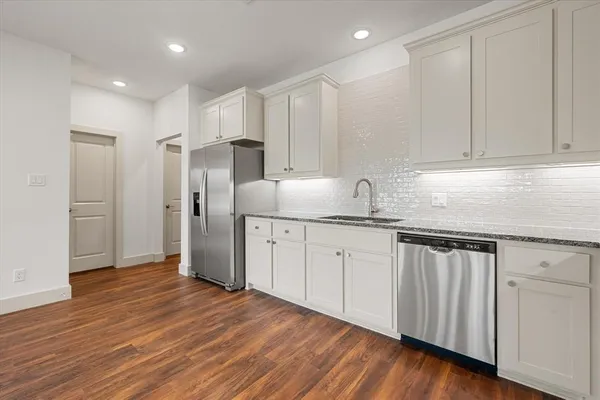 a kitchen with stainless steel appliances granite countertop a refrigerator sink and white cabinets