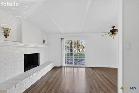 an empty room with wooden floor fireplace and windows