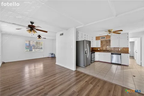 a kitchen with stainless steel appliances kitchen island granite countertop a refrigerator a stove and a sink with wooden floor