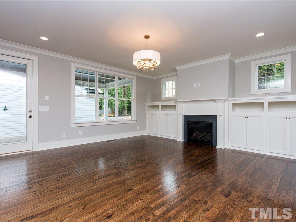 102 Revival Way Raleigh, NC 27608 - Photo 12 of 25 an empty room with wooden floor fireplace and windows