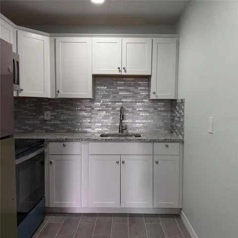 a kitchen with white cabinets granite counter tops and a stove