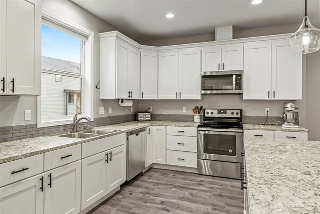 a kitchen with granite countertop a sink stainless steel appliances and cabinets