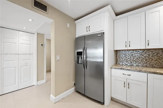 a kitchen with stainless steel appliances granite countertop a refrigerator and white cabinets