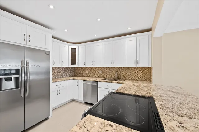 a kitchen with granite countertop a sink stainless steel appliances and white cabinets