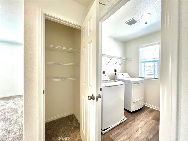 a view of a hallway with white cabinets and wooden floor