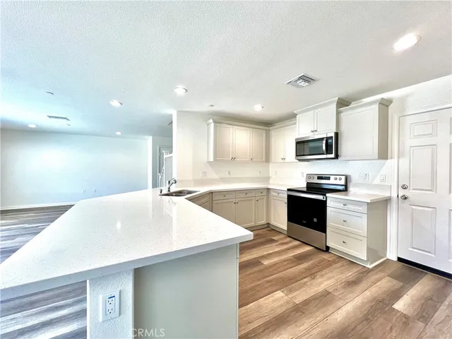 a large white kitchen with kitchen island a sink stainless steel appliances and cabinets