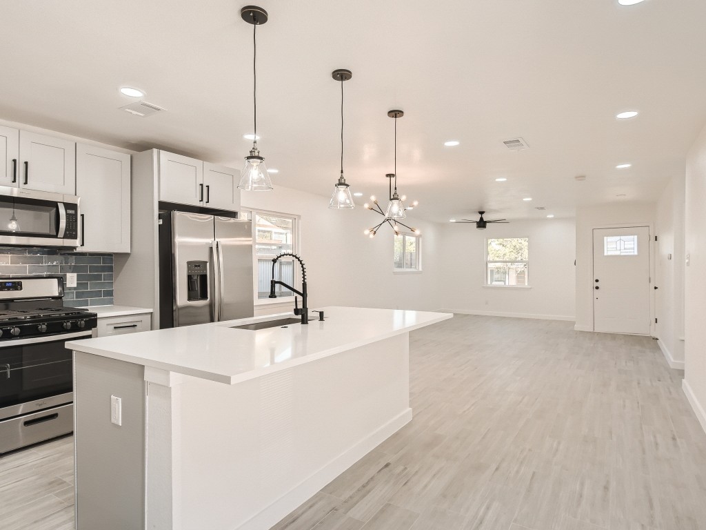 a kitchen with kitchen island a sink stainless steel appliances and white cabinets