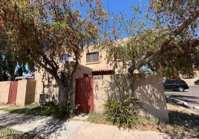 a sign that is sitting in front of a brick house with large windows