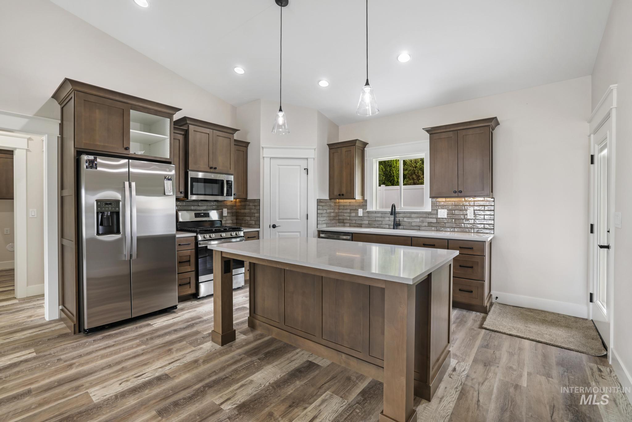 1441 Haizlee Way Twin Falls, ID 83301 - Photo 2 of 26 Kitchen featuring stainless steel appliances, dark wood finish cabinets, backsplash, lofted ceiling, and a center island