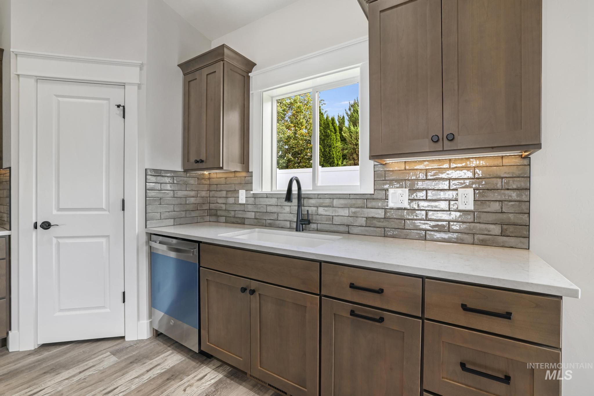 1441 Haizlee Way Twin Falls, ID 83301 - Photo 4 of 26 Kitchen with light stone counters, dishwasher, backsplash, and light wood-style floors