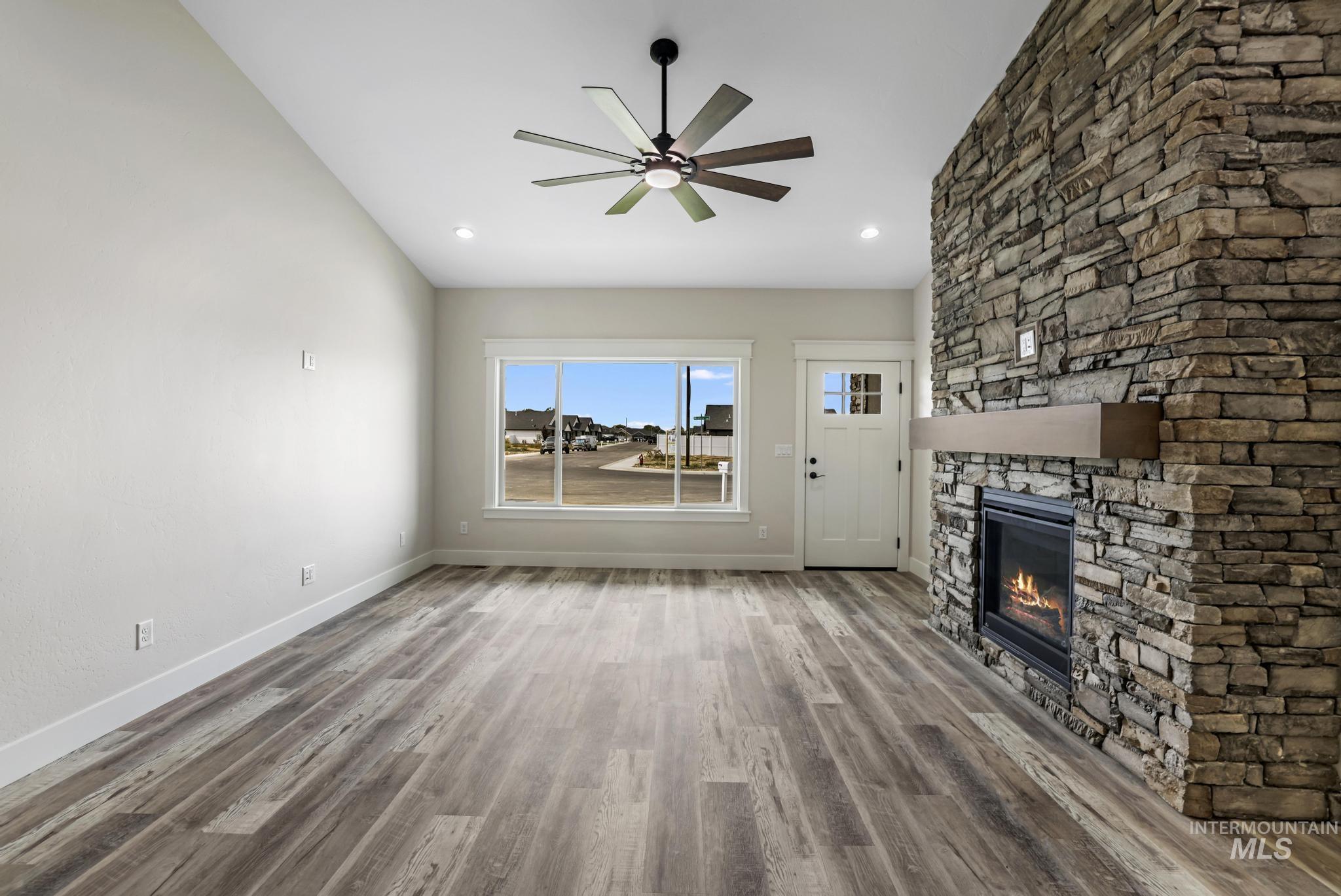 1441 Haizlee Way Twin Falls, ID 83301 - Photo 8 of 26 Unfurnished living room featuring light wood-style flooring, a fireplace, ceiling fan, and recessed lighting