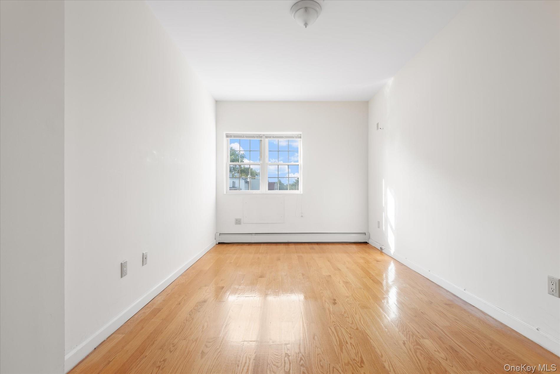 71-05 Cooper Avenue, Unit 2 Queens, NY 11385 - Photo 11 of 15 Spare room with light wood-style flooring and baseboard heating