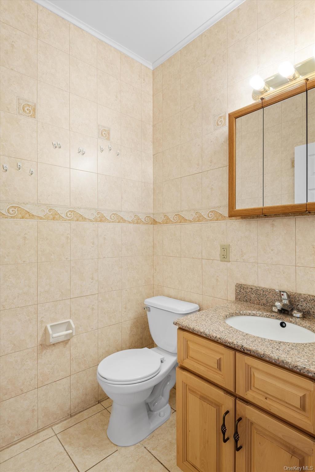 71-05 Cooper Avenue, Unit 2 Queens, NY 11385 - Photo 13 of 15 Half bathroom with vanity, tile walls, light tile patterned flooring, and ornamental molding