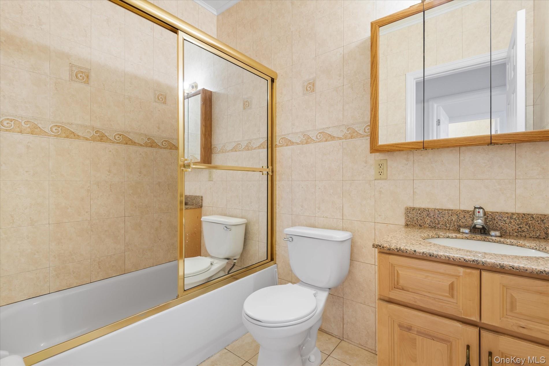 71-05 Cooper Avenue, Unit 2 Queens, NY 11385 - Photo 14 of 15 Full bath with vanity, tile walls, combined bath / shower with glass door, and light tile patterned floors