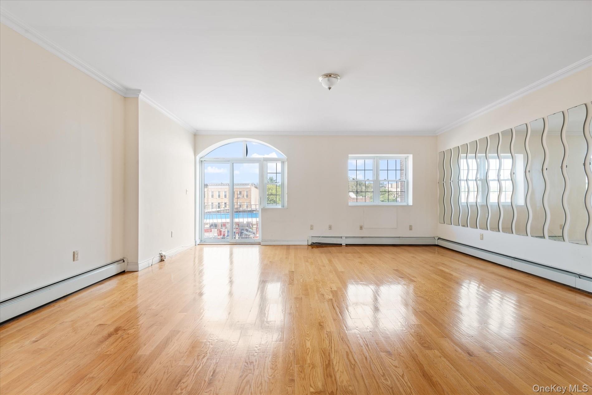 71-05 Cooper Avenue, Unit 2 Queens, NY 11385 - Photo 2 of 15 Spare room featuring light wood-style flooring, ornamental molding, and a baseboard radiator