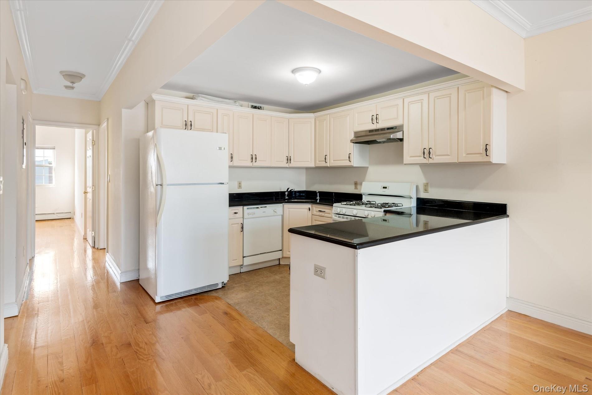 71-05 Cooper Avenue, Unit 2 Queens, NY 11385 - Photo 6 of 15 Kitchen featuring white appliances, ornamental molding, light wood-style floors, a peninsula, and under cabinet range hood