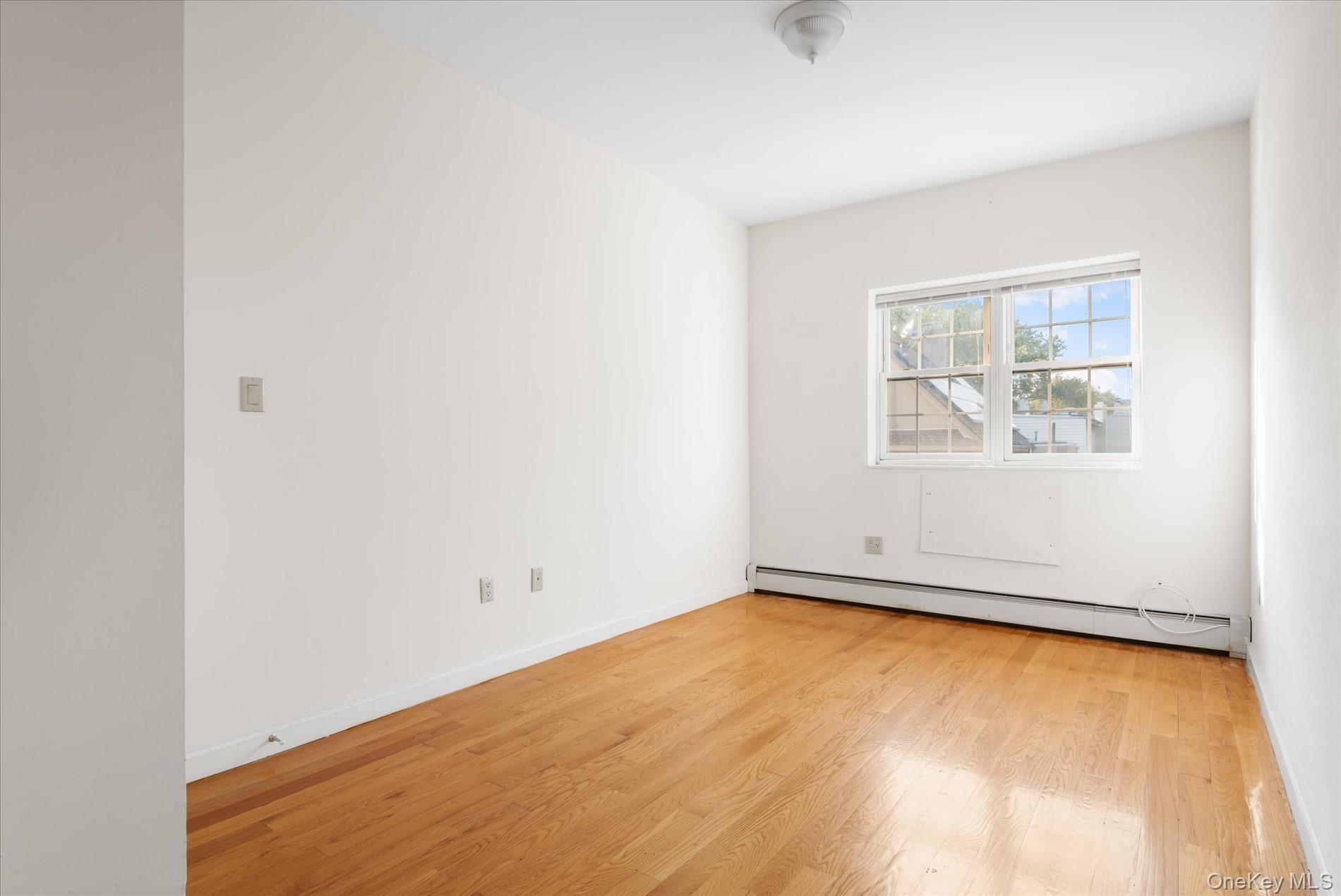 71-05 Cooper Avenue, Unit 2 Queens, NY 11385 - Photo 9 of 15 Empty room featuring light wood-style floors and baseboard heating