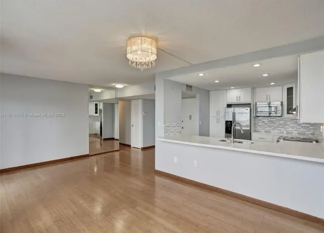 an empty room with wooden floor and a kitchen
