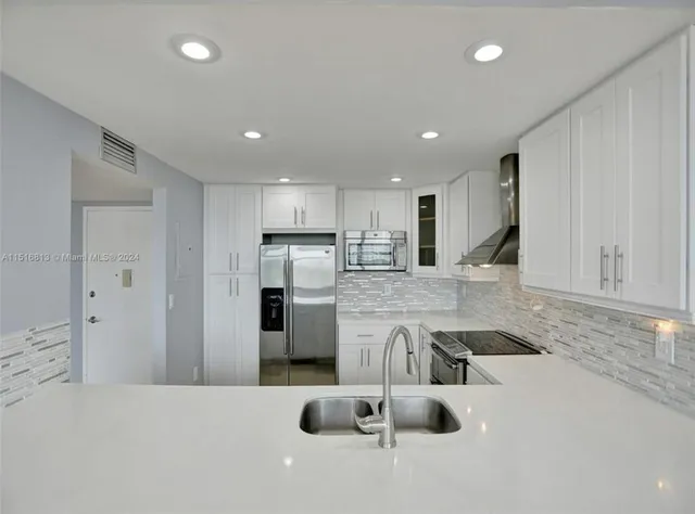 a kitchen with stainless steel appliances granite countertop a sink refrigerator and cabinets