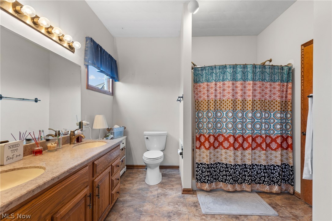 64508 Slade Road Cambridge, OH 43725 - Photo 20 of 50 1st floor primary Full bathroom featuring double vanity and a shower with curtain