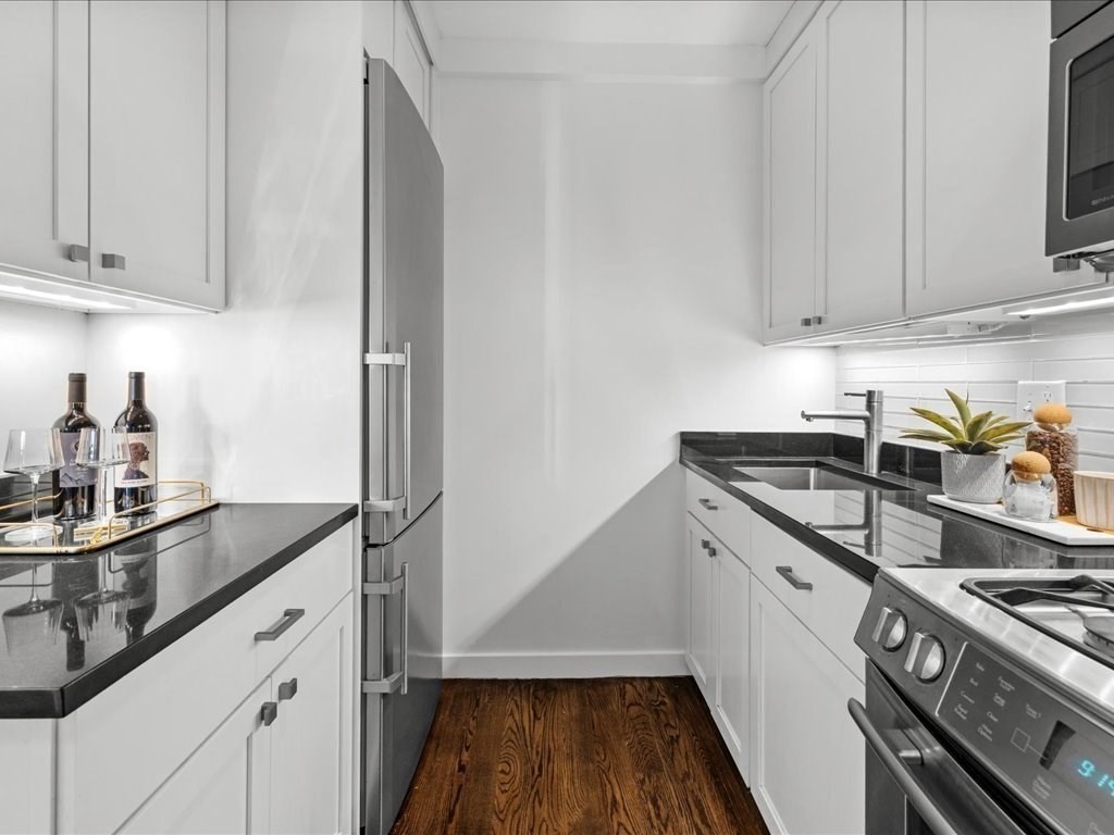 65 East India Row, Unit 33A Boston, MA 02110 - Photo 15 of 36 a kitchen with granite countertop a sink stove and cabinets