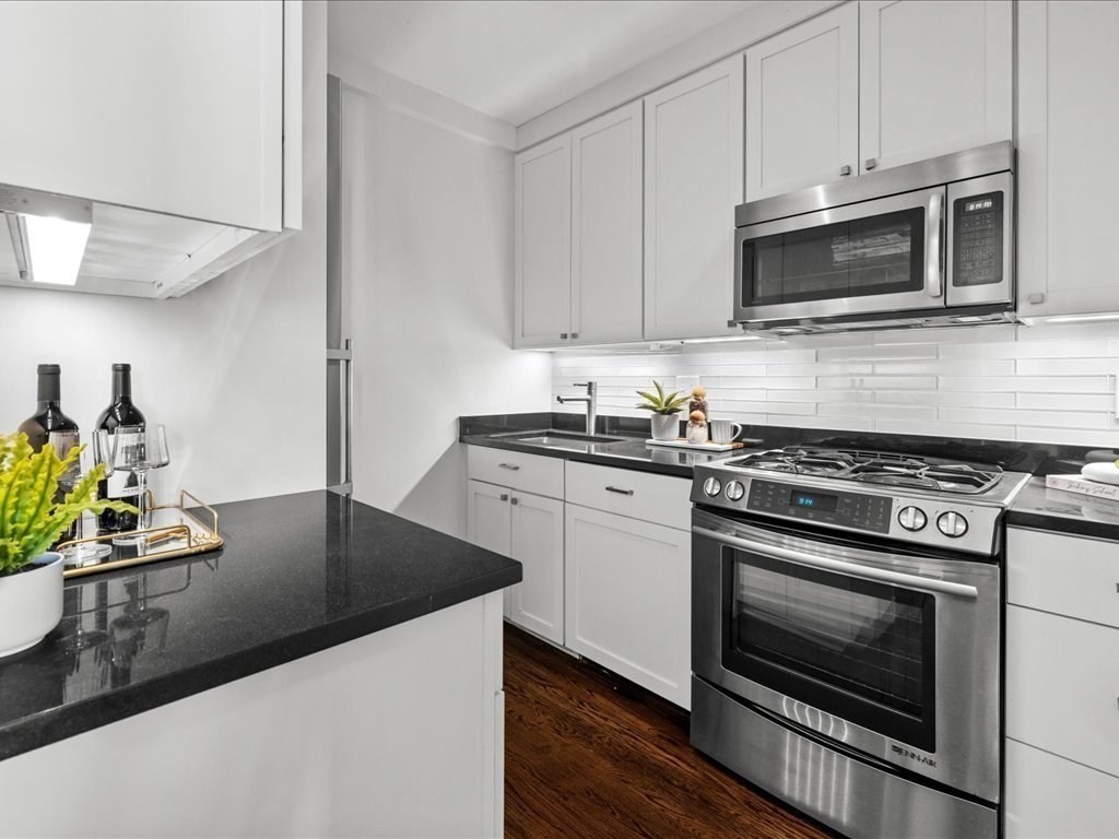 65 East India Row, Unit 33A Boston, MA 02110 - Photo 17 of 36 a kitchen with stainless steel appliances a stove a microwave sink and cabinets
