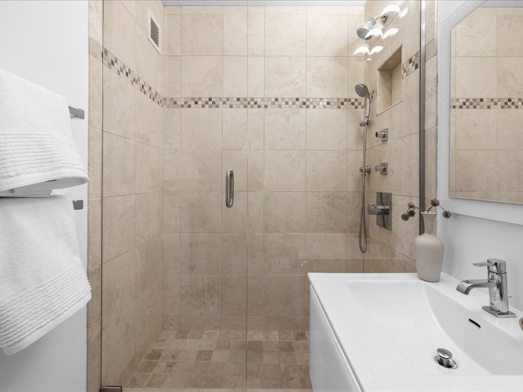 65 East India Row, Unit 33A Boston, MA 02110 - Photo 22 of 36 a bathroom with a sink a shower and a mirror