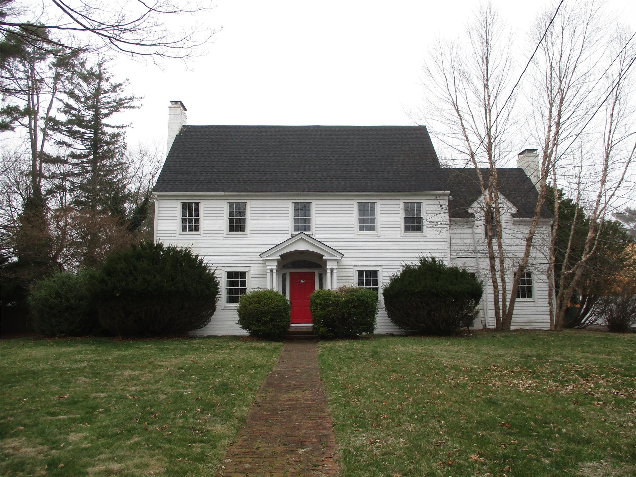 Colonial home with a front lawn, a chimney, and a shingled roof