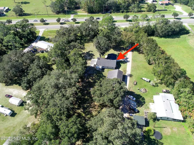an aerial view of residential house with outdoor space and trees all around