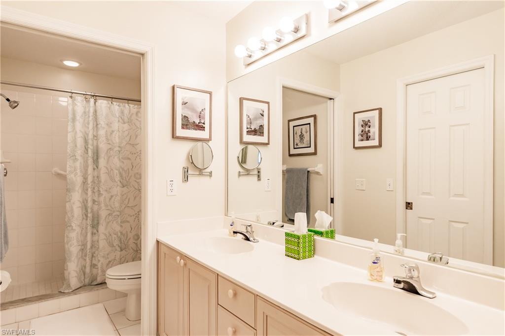 320 Gabriel Circle, Unit 3608 Naples, FL 34104 - Photo 12 of 32 a bathroom with a granite countertop sink a toilet a shower and a mirror