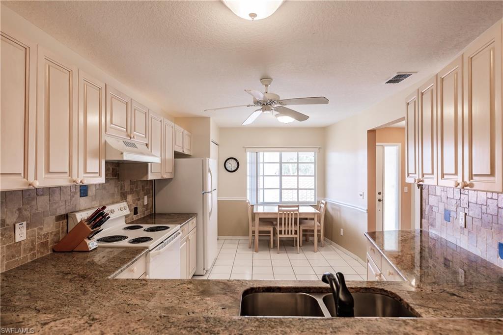 320 Gabriel Circle, Unit 3608 Naples, FL 34104 - Photo 7 of 32 a kitchen with granite countertop a stove a sink a dining table and chairs with wooden floor